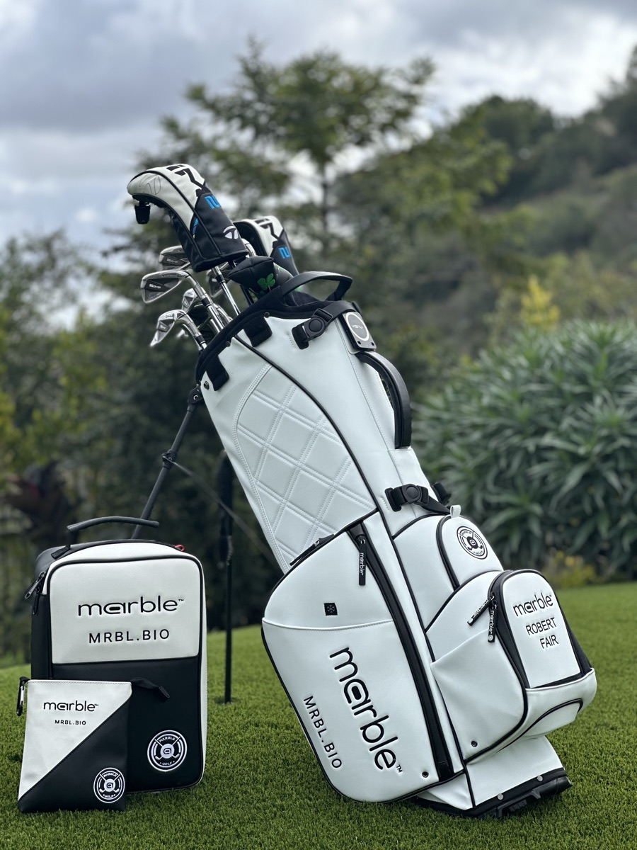 Low angle of the white Marble stand bag, diamond-quilted leather and black trim against a stormy sky